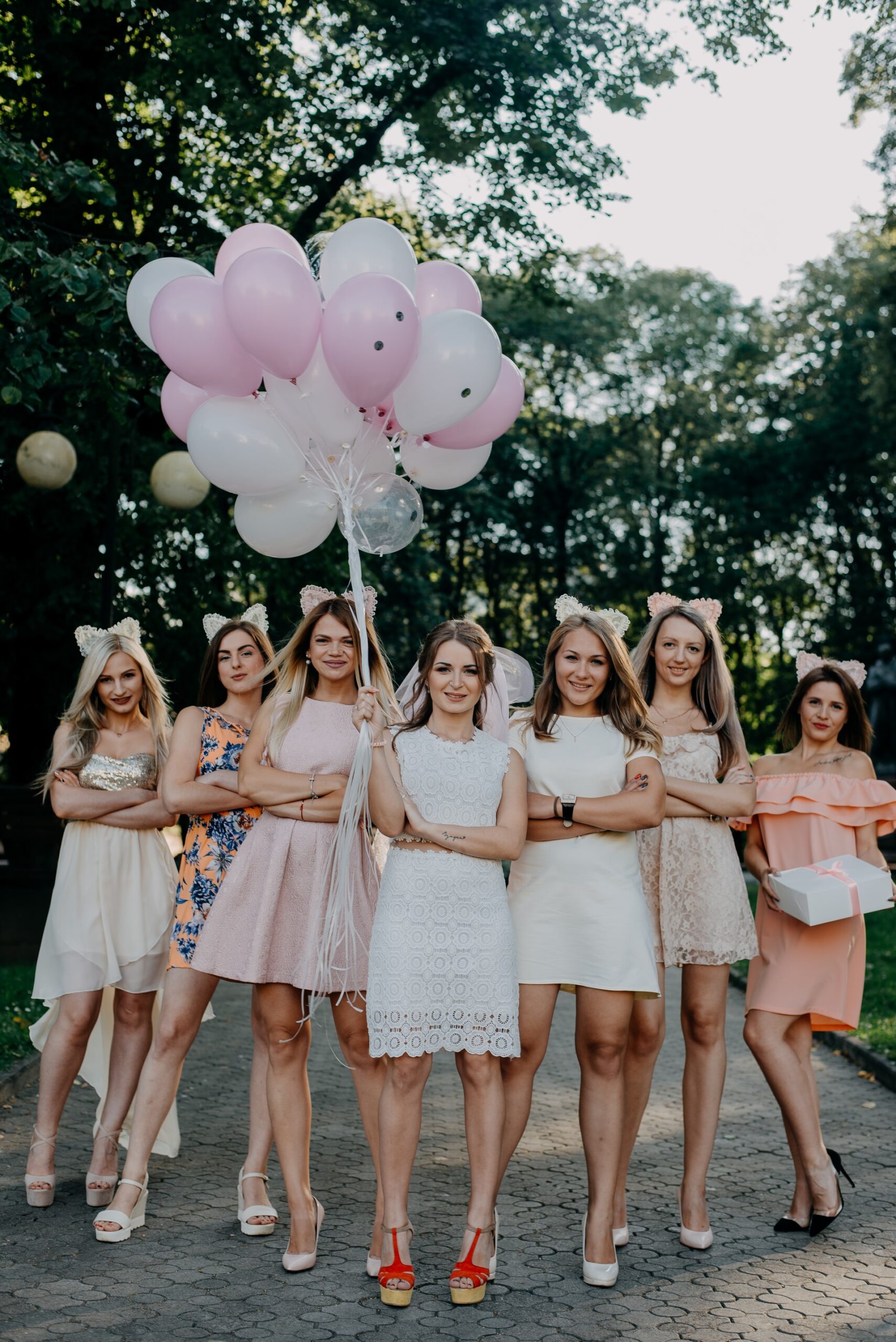 perfect wedding guest outfit, women wedding guests in a row holding pink balloons