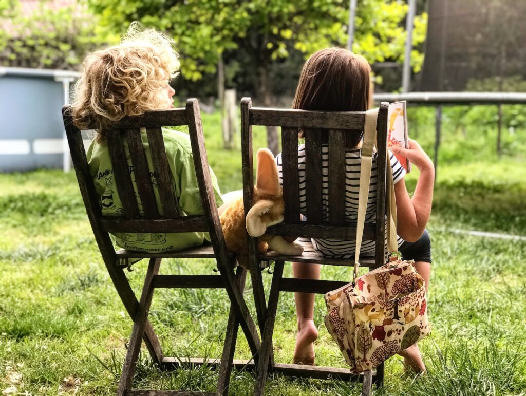 children sitting on deck chairs on the grass