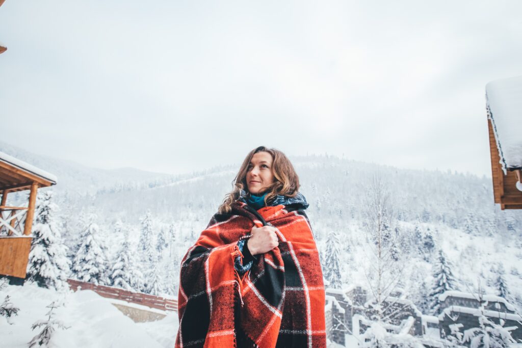 Christmas ski holiday woman in ski chalet wrapped in a blanket